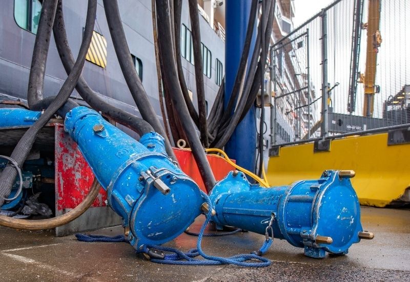 Blå kraftige elkabler og stik ved et skib i havnen