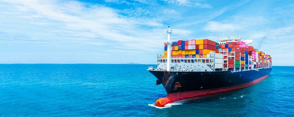 Containerskib med farverige containere sejler på åbent hav